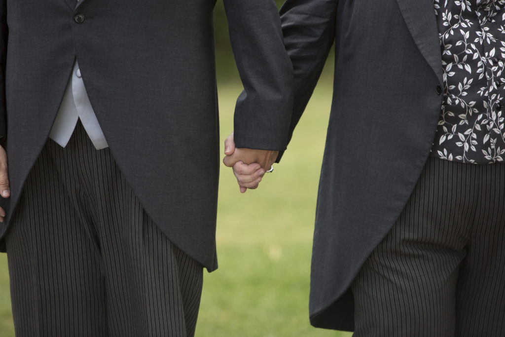 Grooms holding hands after their wedding ceremony