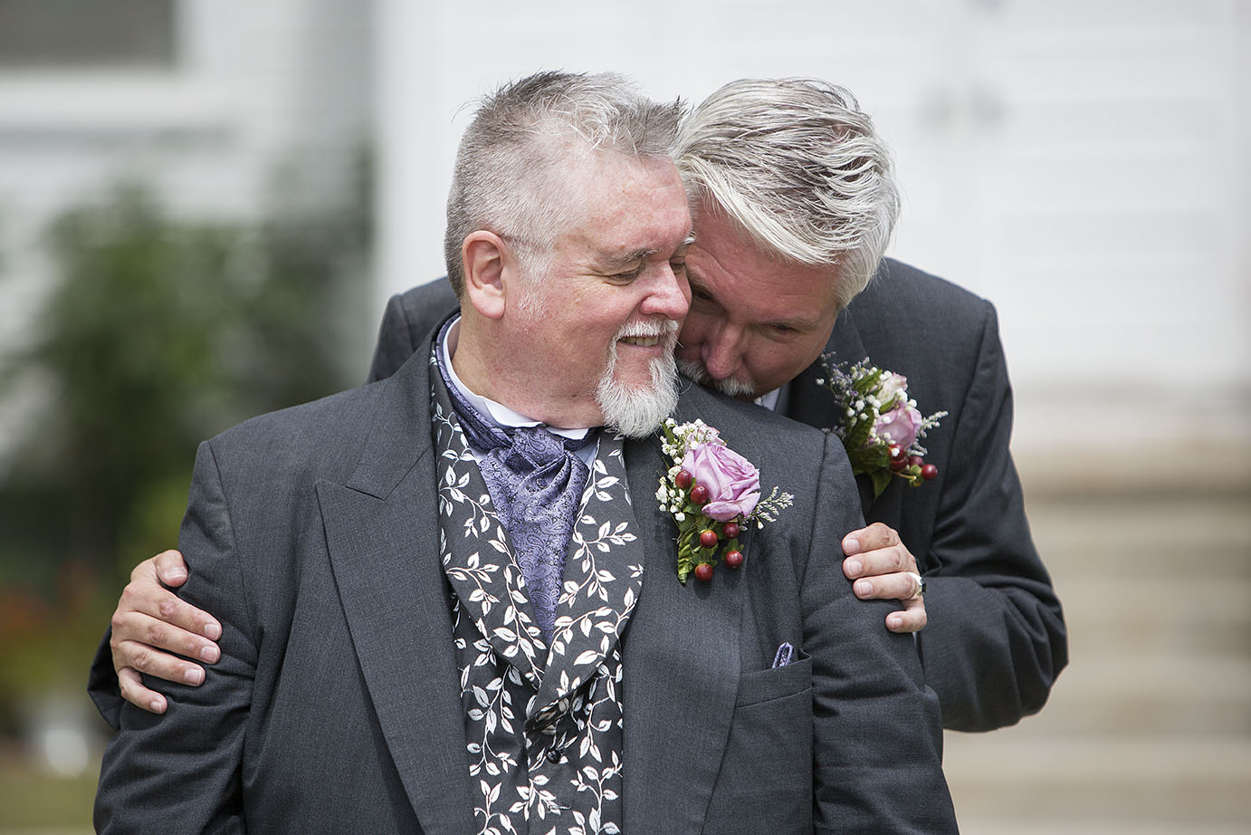 Michigan LGBTQ+ wedding photographer - groom hugging his groom from behind while kissing his shoulder