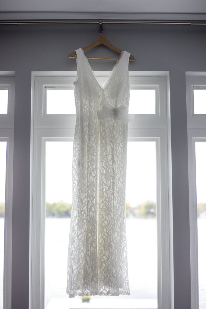 White lace dress hanging in front of a window overlooking Cavanaugh Lake in Chelsea, Michigan