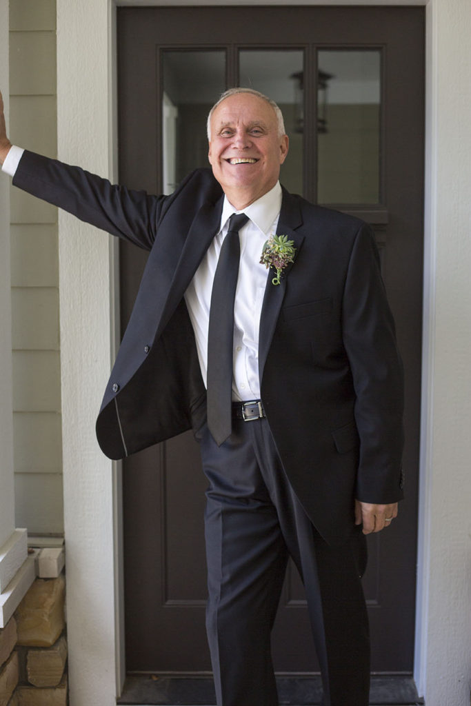 Dapper groom poses on the front porch of their Chelsea home