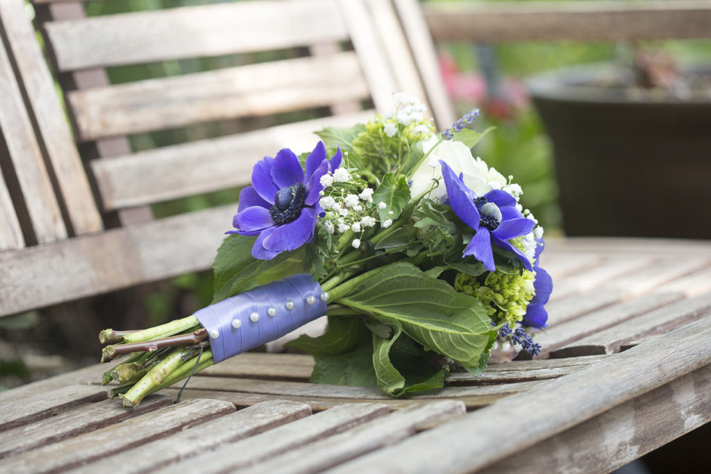 Purple and green bouquet laying on a bench inside the Belle Isle Conservatory