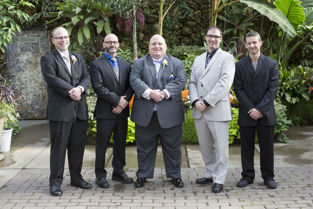 Groom and groomsmen posing together on in the Belle Isle Conservatory