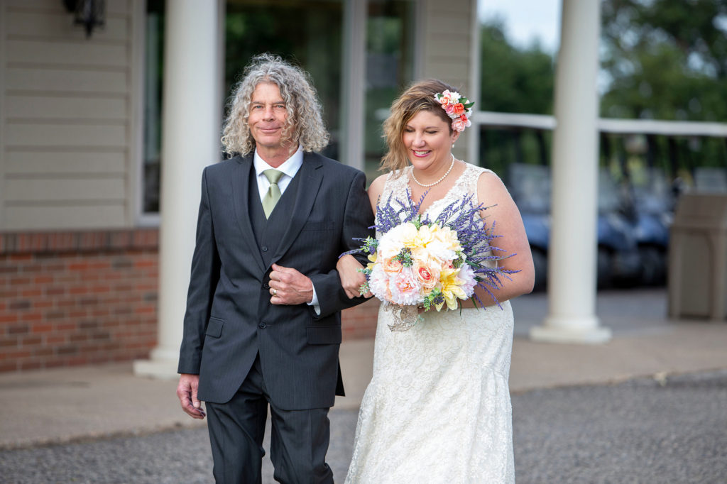 Emily and her dad walking down the aisle to meet her bride