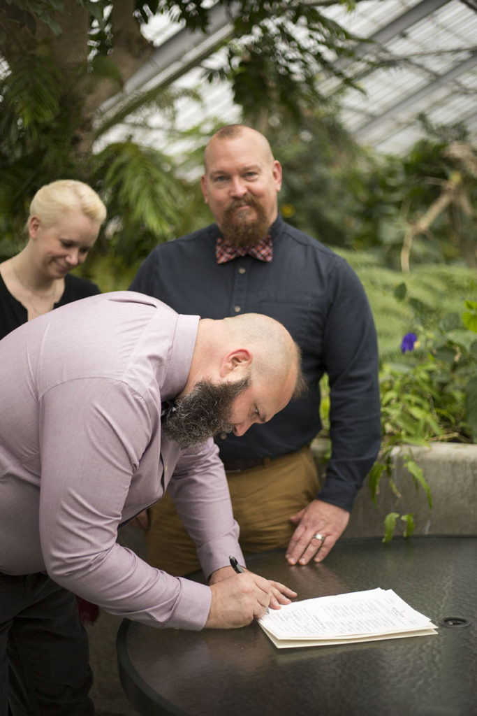 LGBTQ wedding couple signs marriage license at October wedding