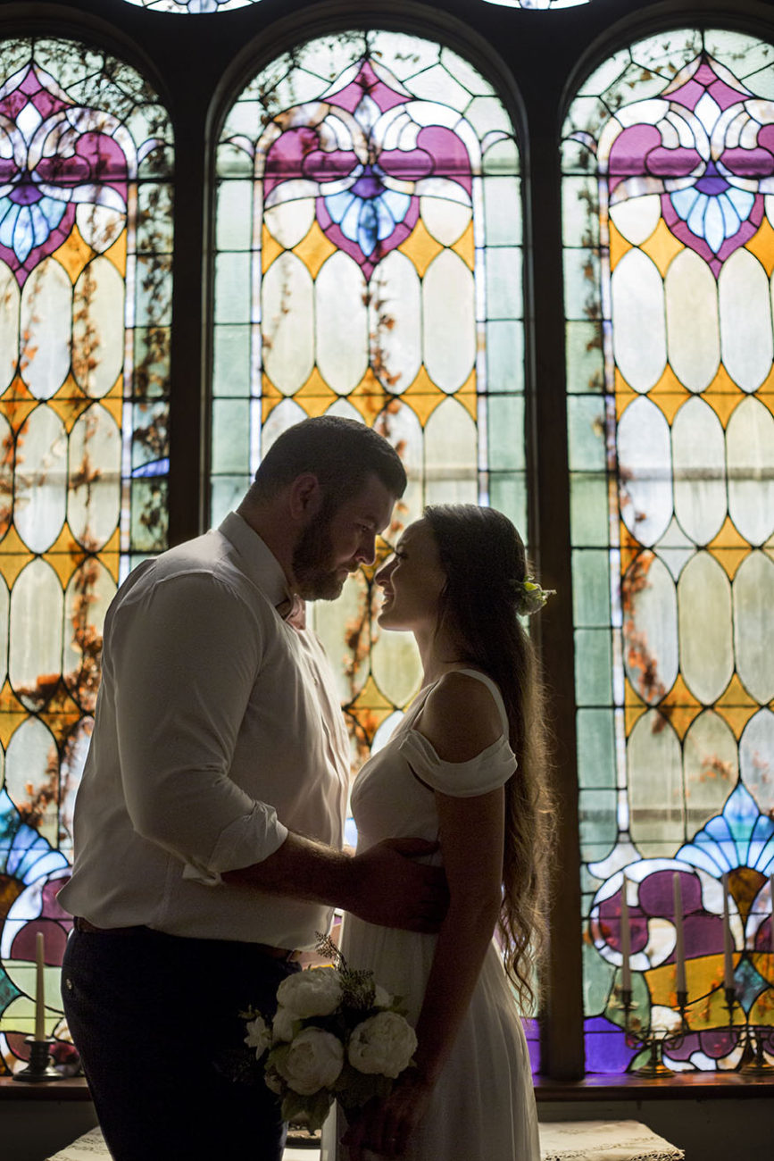 Bride and Groom in front of historic stained glass at Celebrations Wedding Chapel