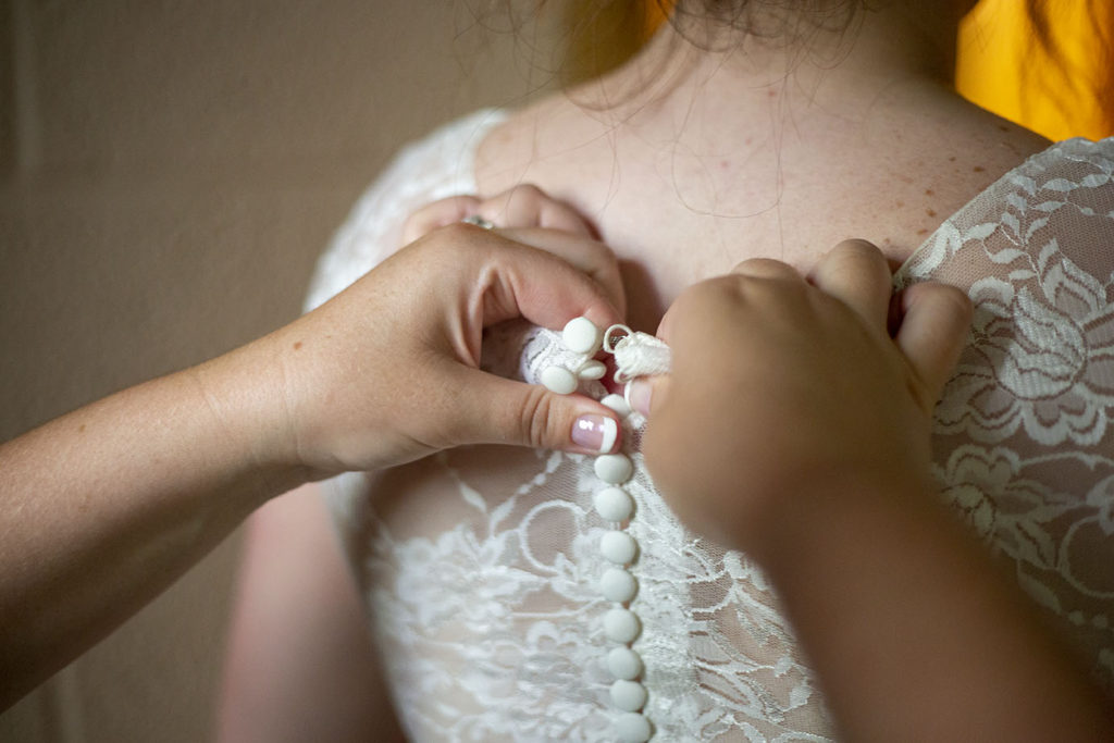 Bride's mother helps button the back of her dress