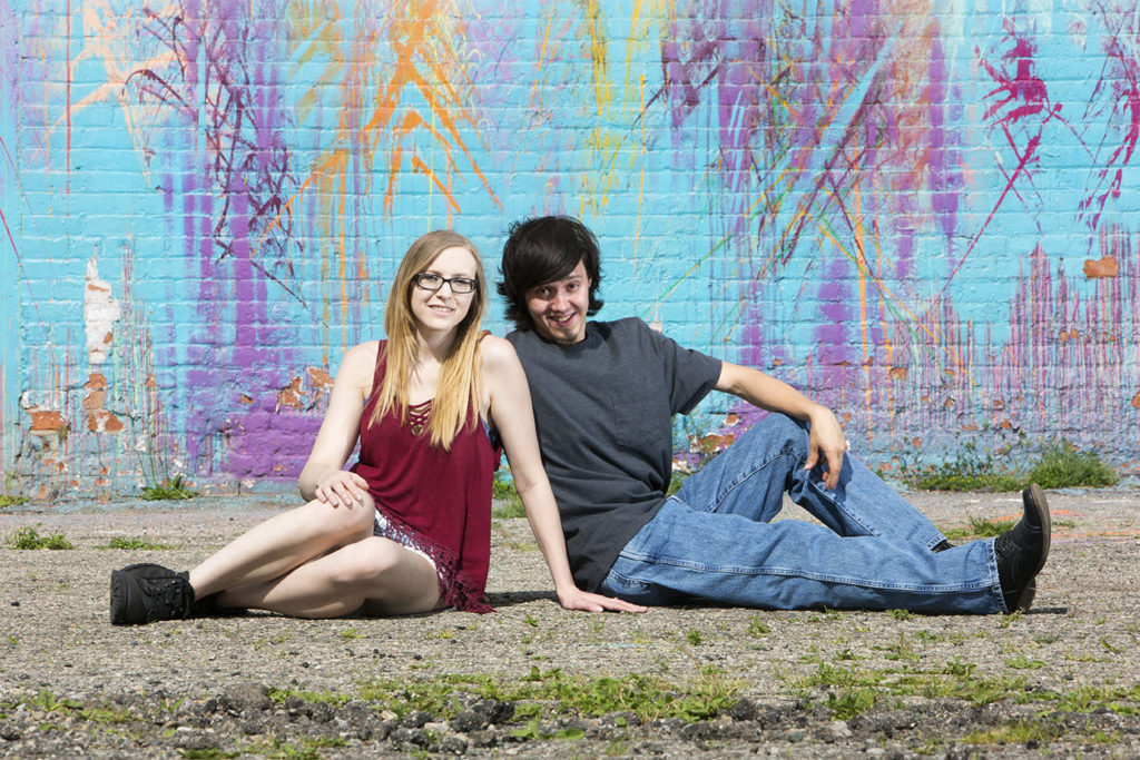 Couple sits in front of a mural for their Detroit urbex engagement session