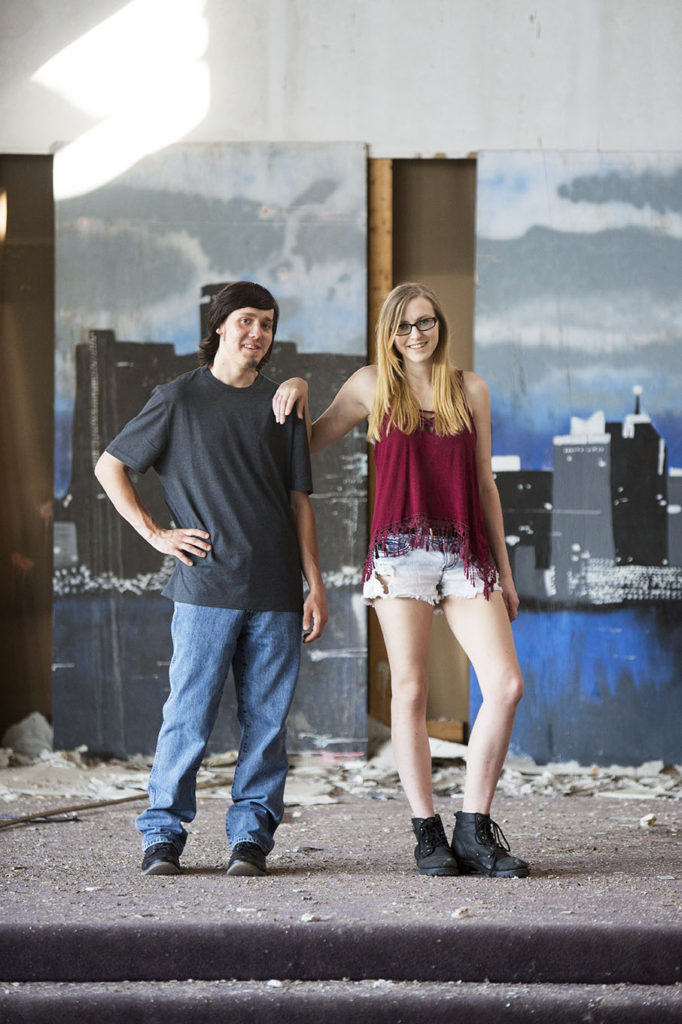 Detroit urbex engagement session poses on the stage at abandoned Catholic school