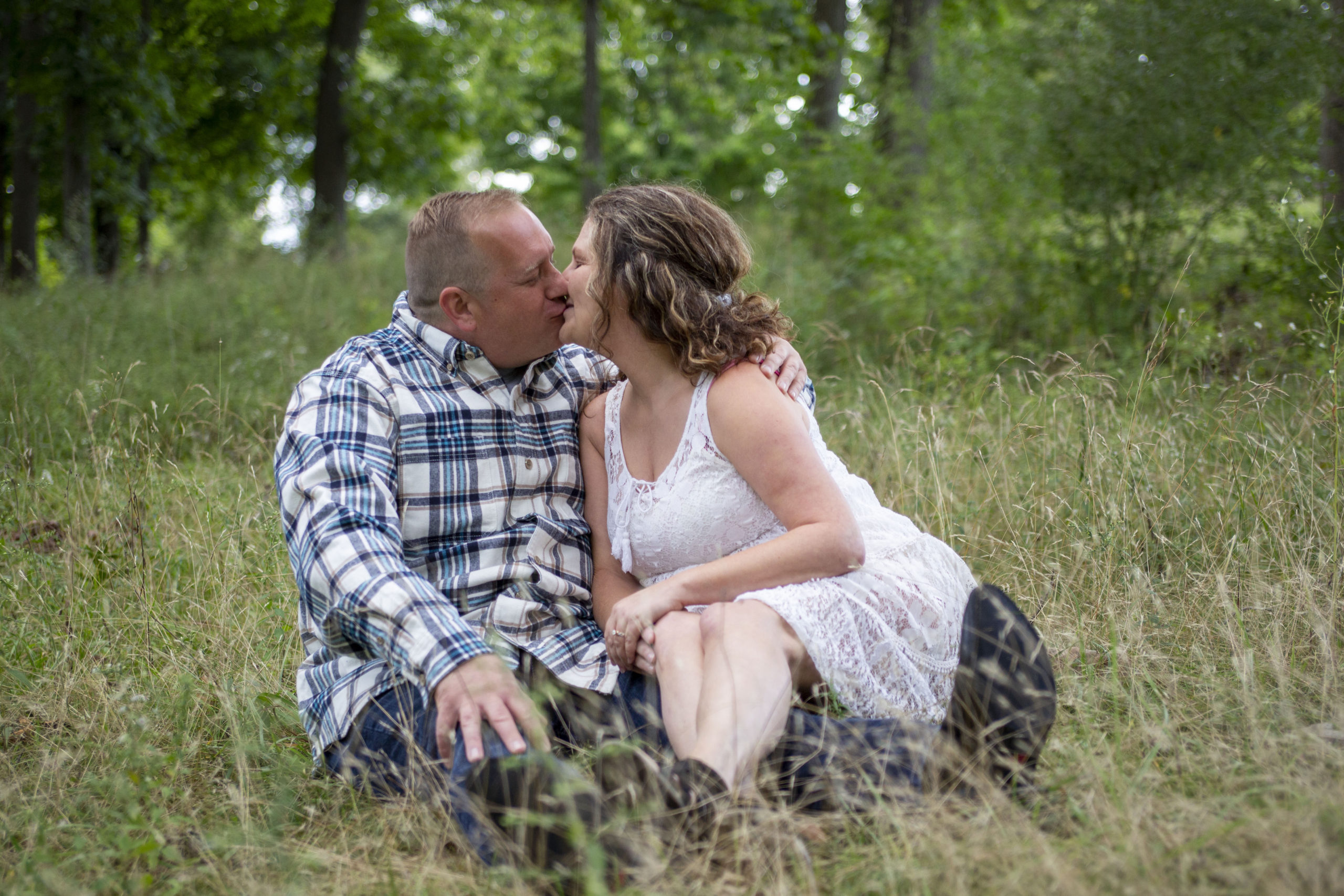 Couple sits among tall grass for their Dexter engagement session