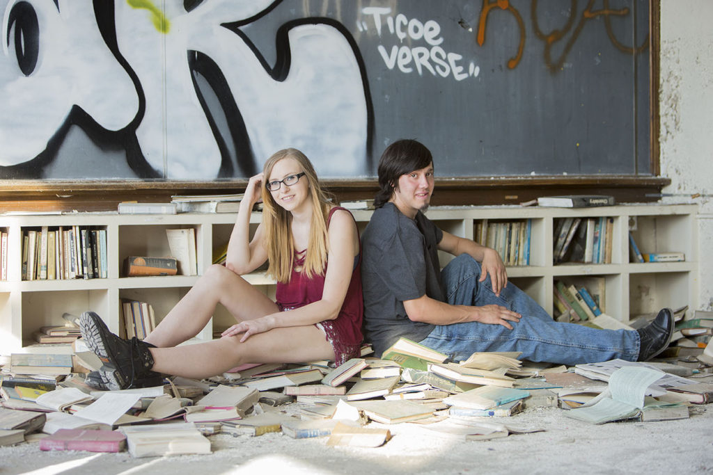 Engaged couple poses in the scattered books