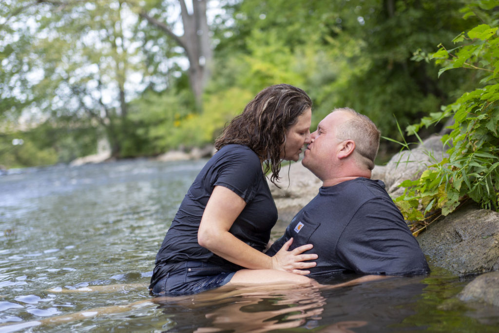 Lola straddles Chris in the river