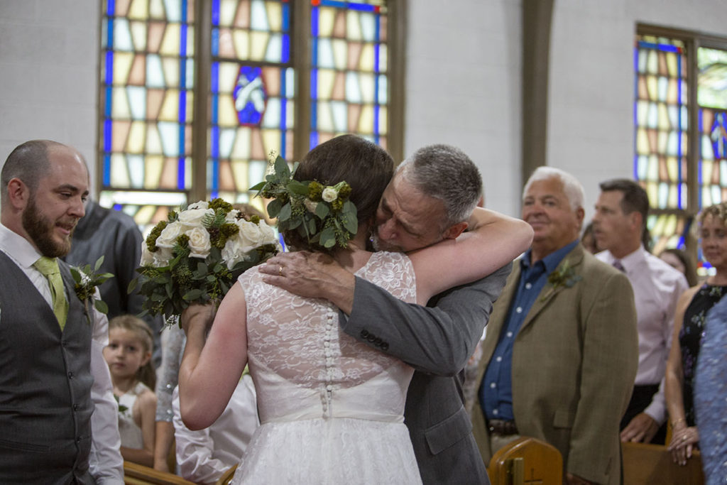 Father hugs bride as he hands her off