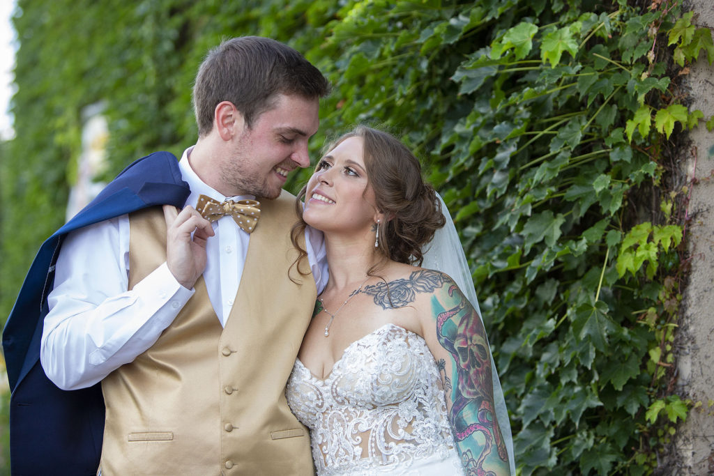 Couple poses in front of wall covered in ivy