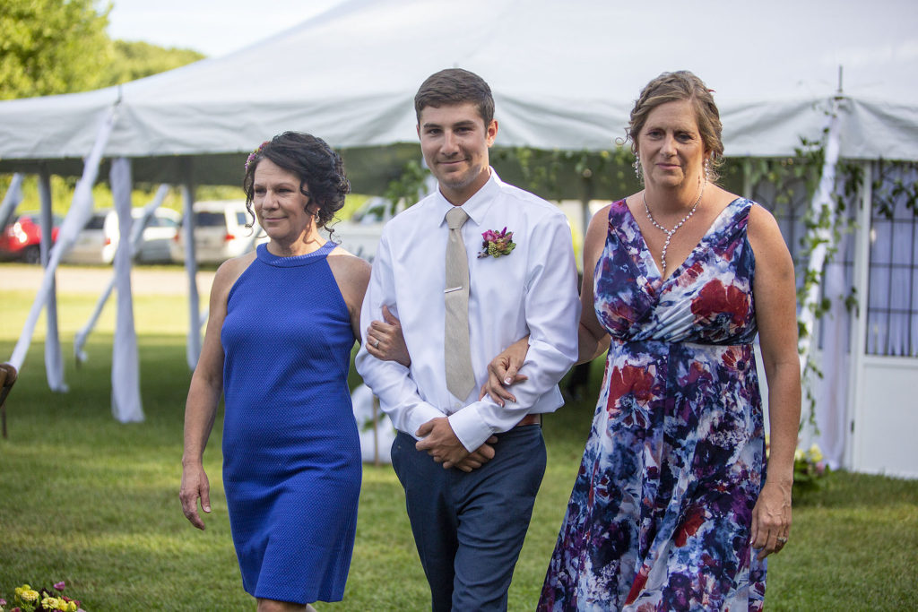 Groom being escorted down the aisle by moms