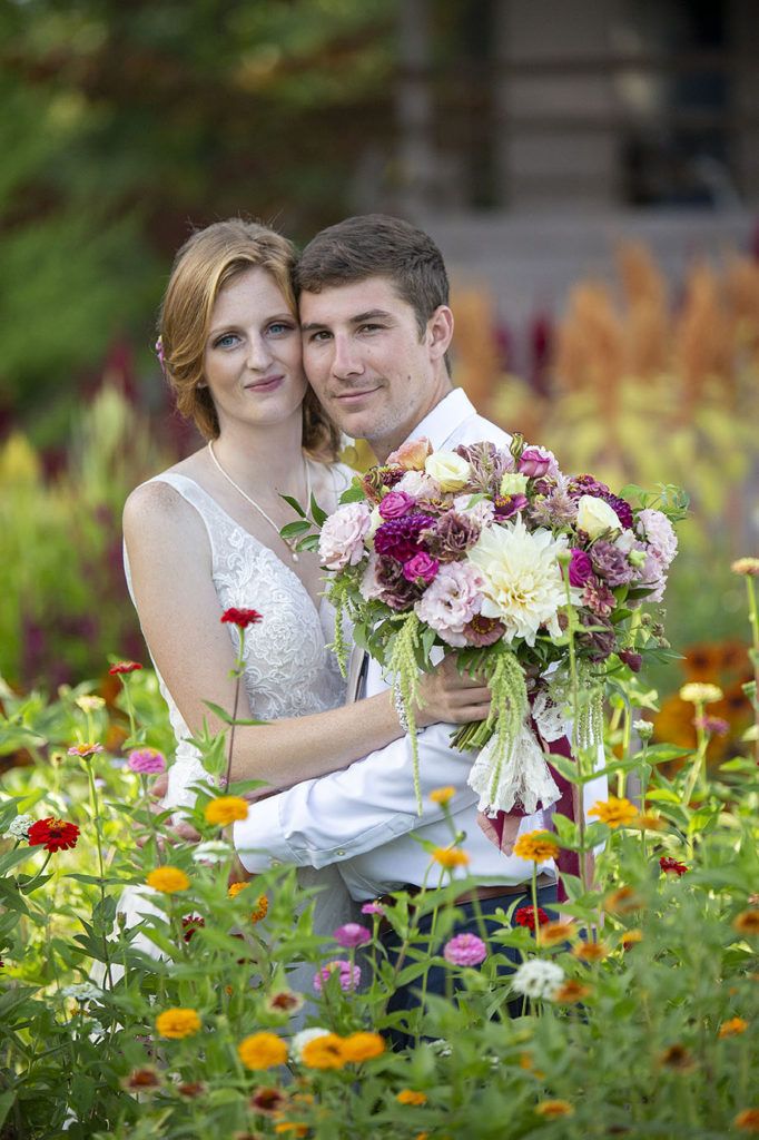 Carmen and Chris stand in the garden amongst the dahlias