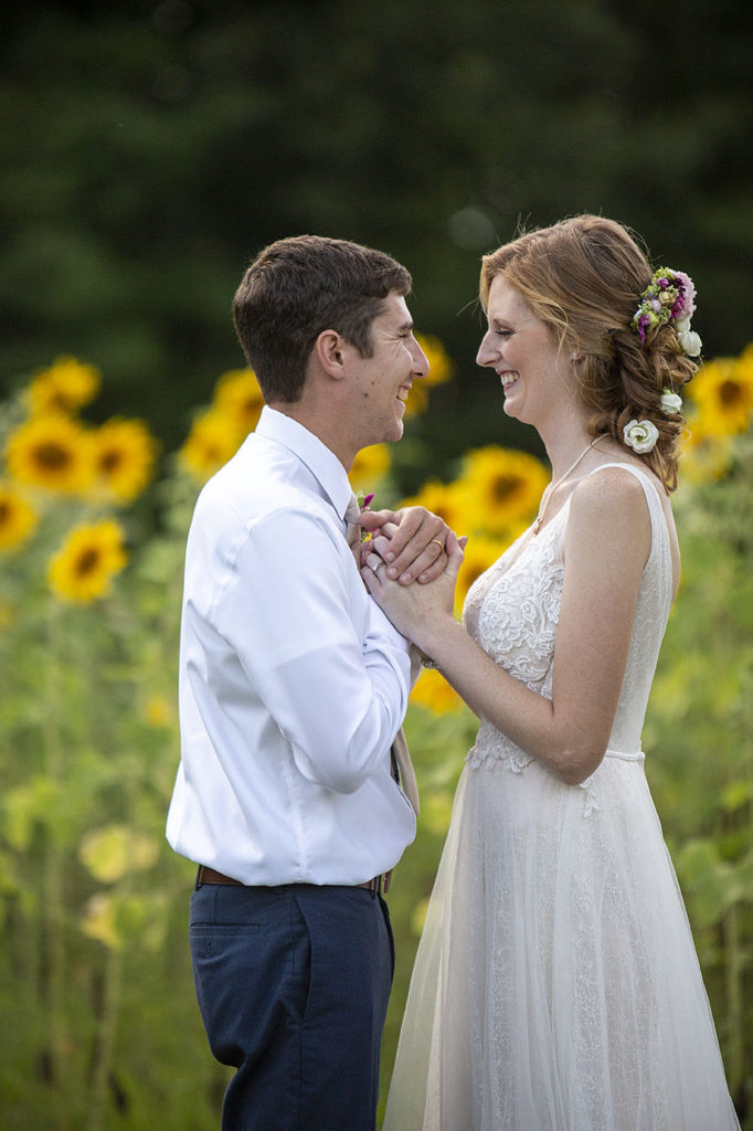 Carmen and Chris look at each other in front of sunflower field