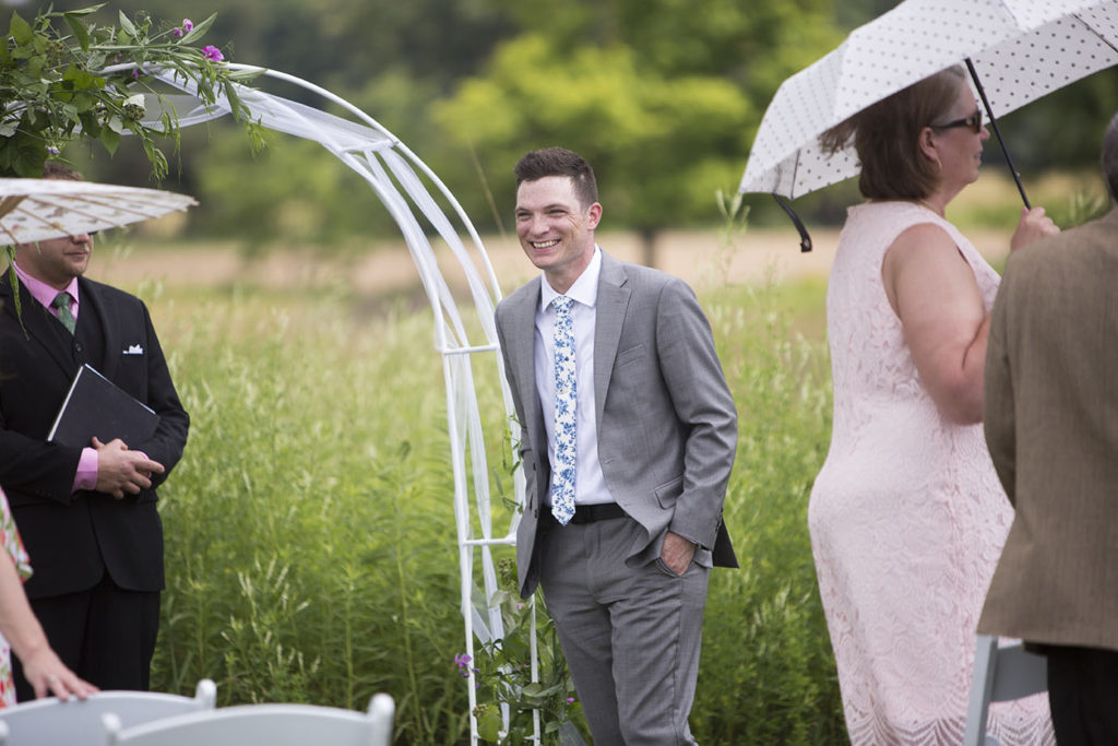 Groom smiling as he sees his bride approaching the Ypsilanti wedding ceremony