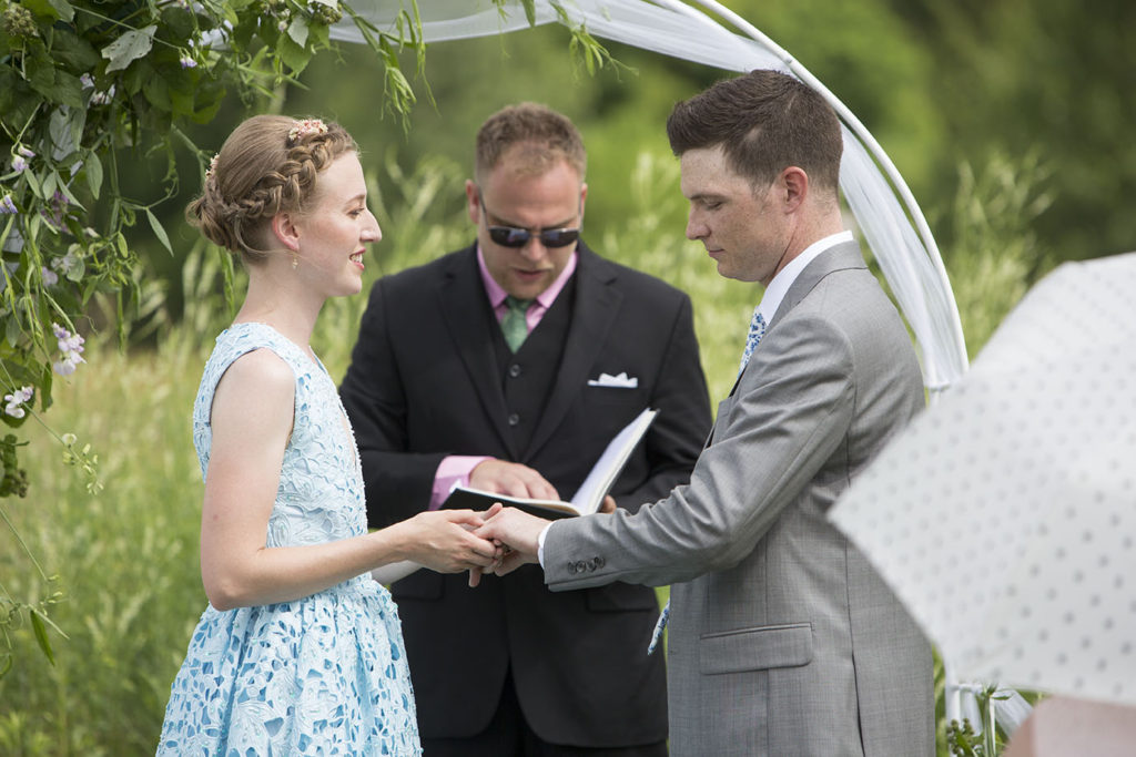 Bride putting ring on groom during Ypsilanti wedding