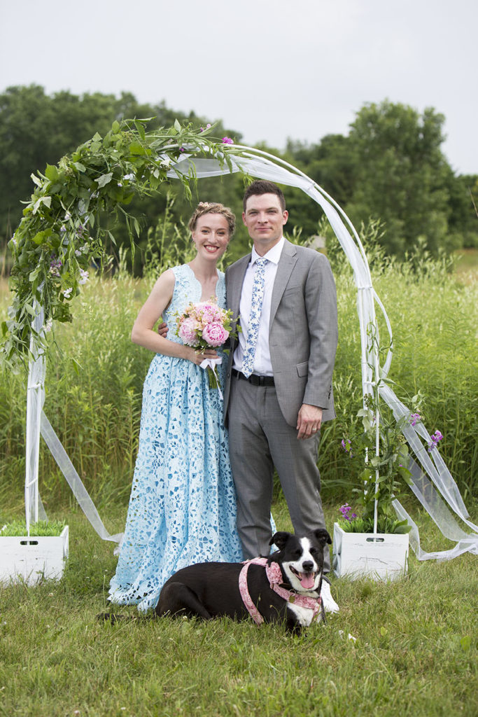 Ypsilanti wedding couple poses next to floral arch