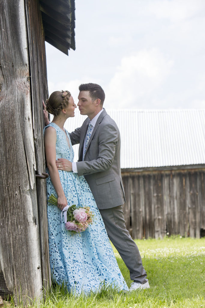 Groom kissing bride leaning against antique barn Ypsilanti wedding