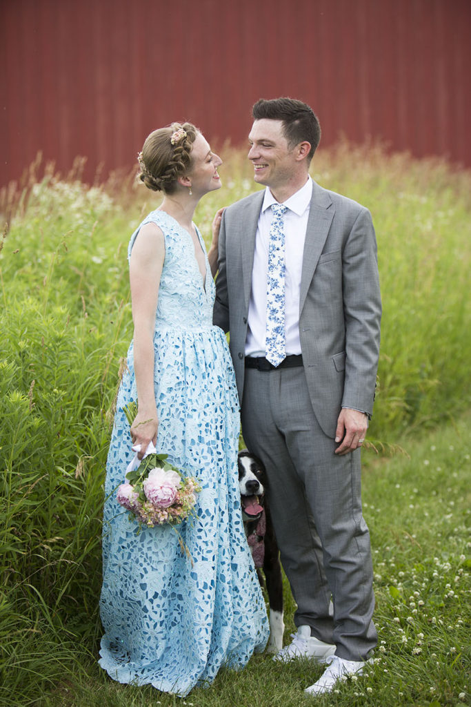 Dog peeks out from between the couple after Ypsilanti wedding