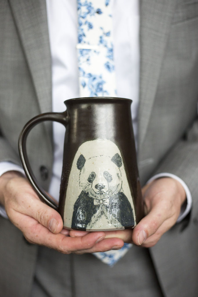 Groom holding custom painted panda mug Corner Brewery wedding reception