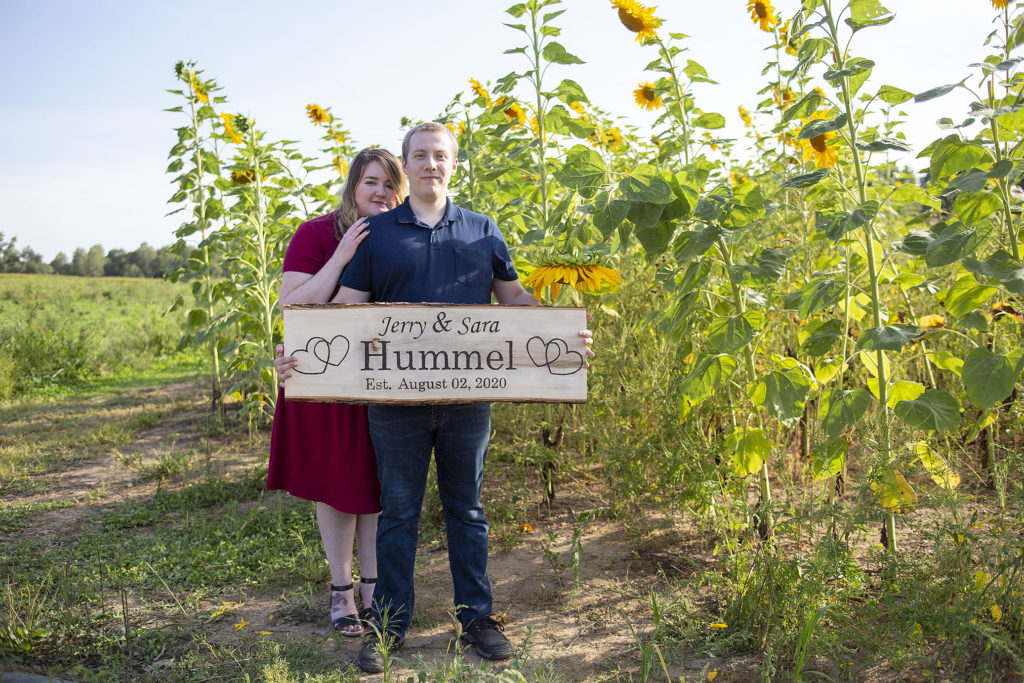 Couple holding sign with their last name and wedding date