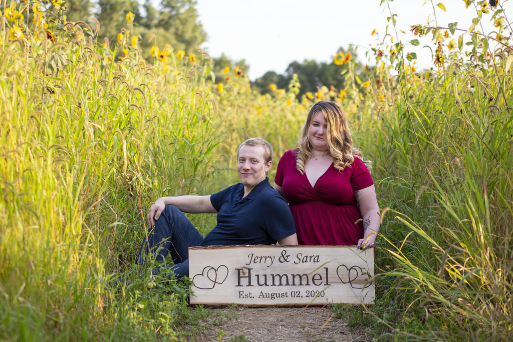 Couple posing between rows of sunflowers