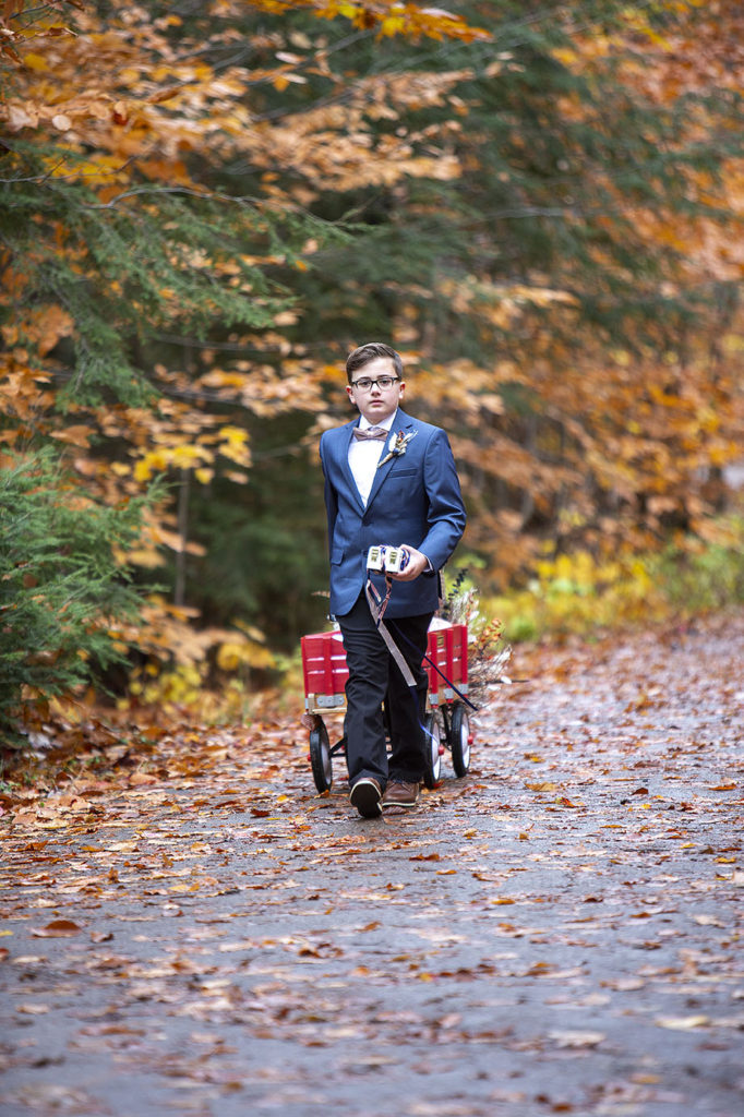 Son of bride walking down the aisle pulling wagon