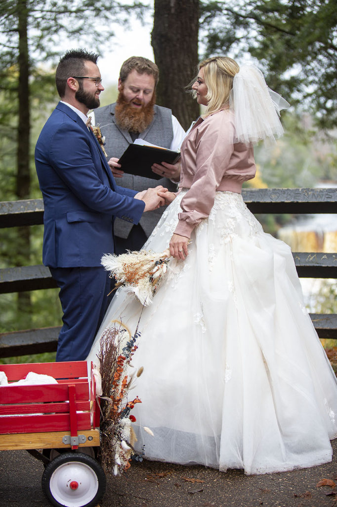 Groom putting ring on bride's hand at Northern Michigan wedding