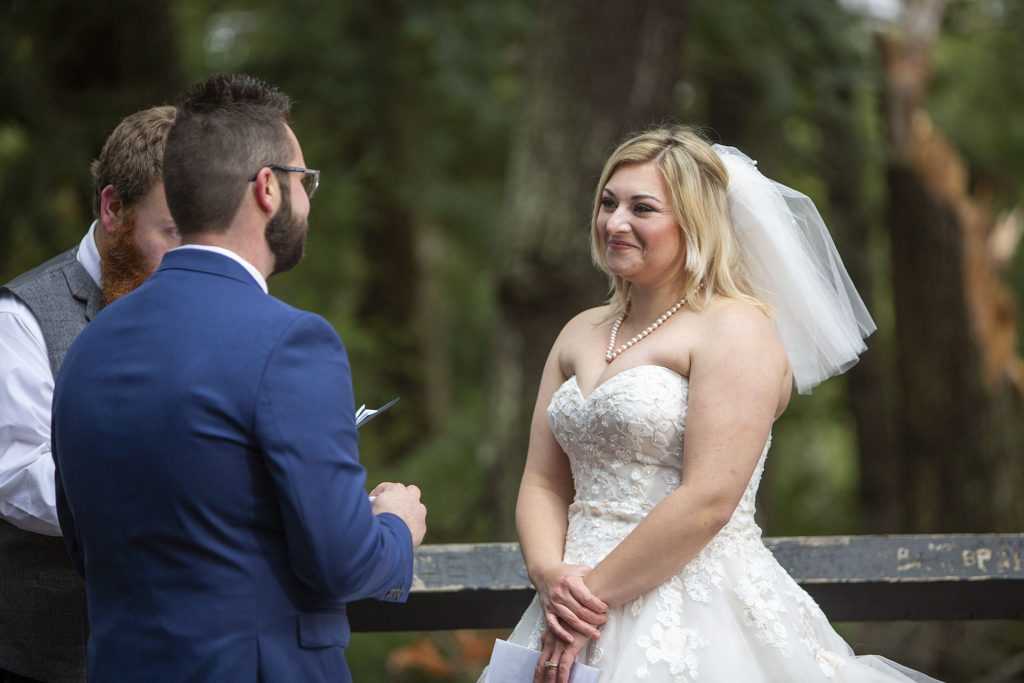 Bride smiling at groom as he reads wedding vows Tahquamenon Falls elopement