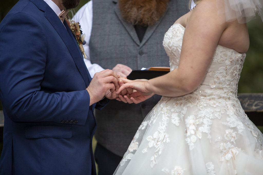 Groom putting ring on bride's hand during Tahquamenon Falls elopement