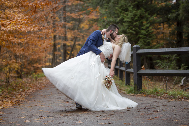 Groom dips bride for a kiss while snow falls all around them in Northern Michigan