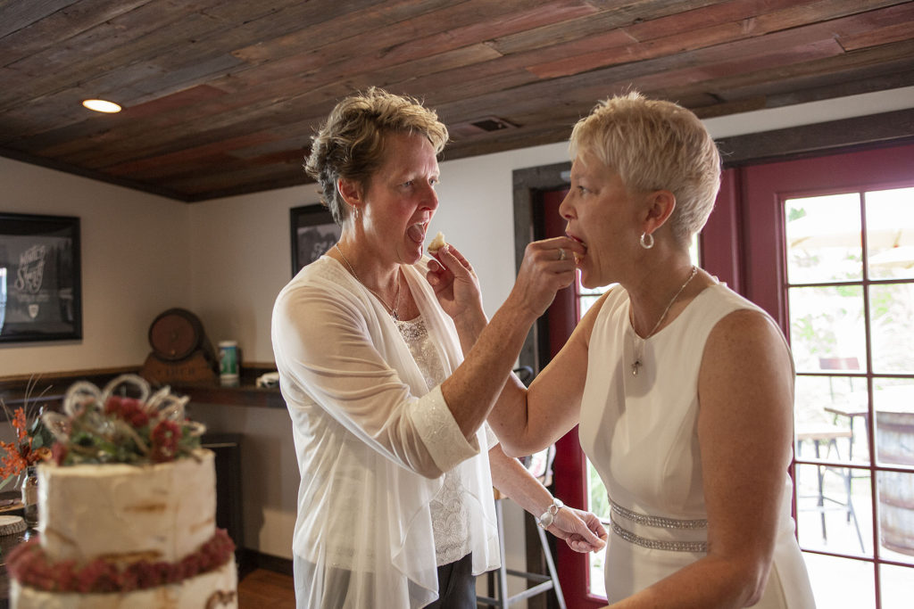 Michigan bride and bride feeding each other cake