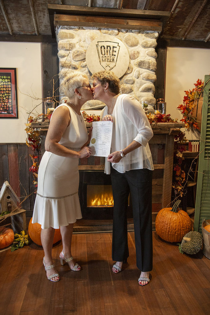 Detroit LGBTQ couple kissing with marriage certificate