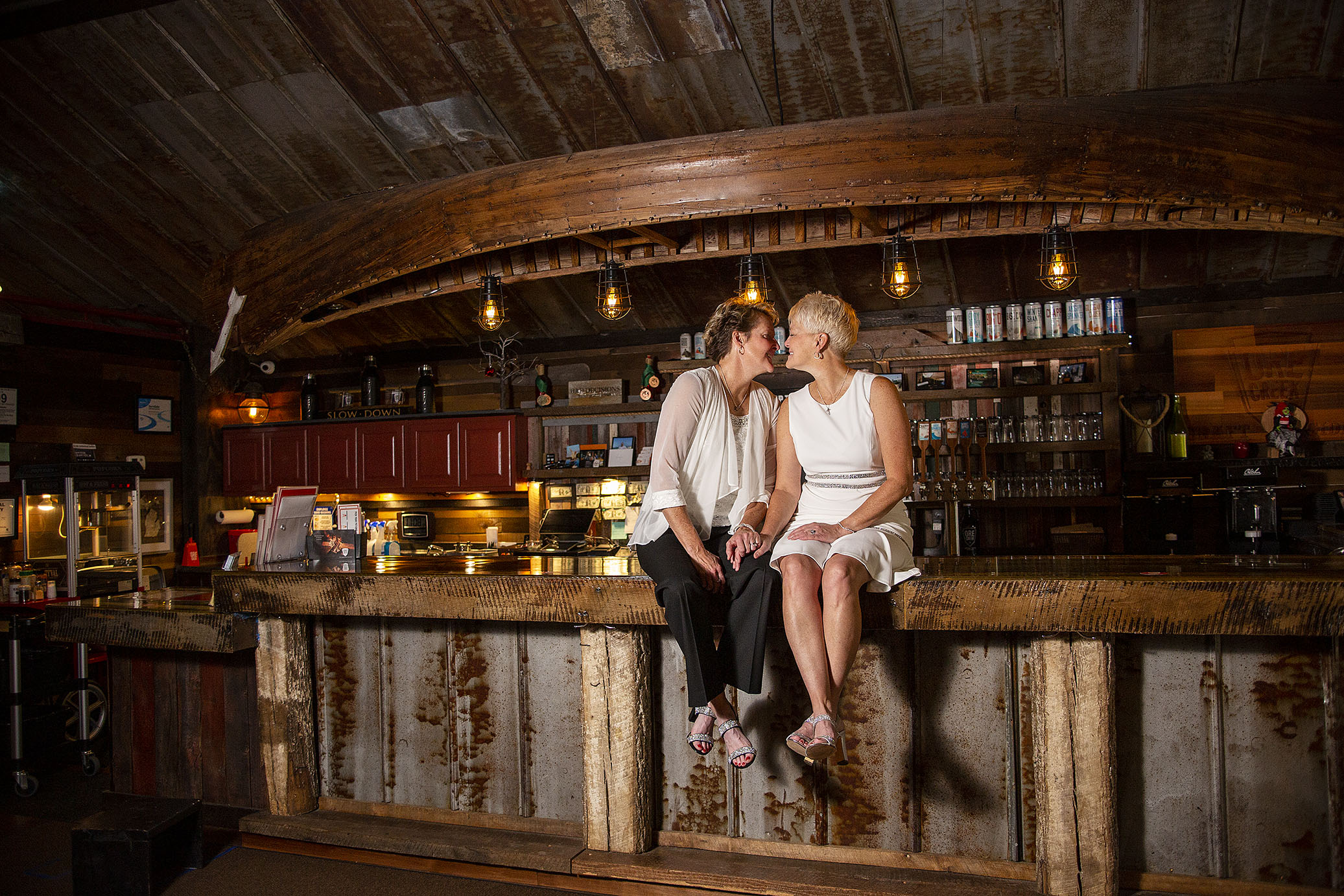 Lesbian couple kissing on top of the bar top at Ore Creek Cidery in Pinckney