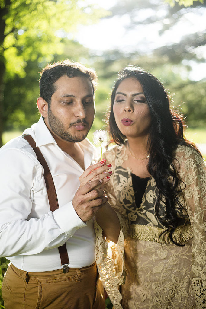 Boho wedding couple blows on a dandelion