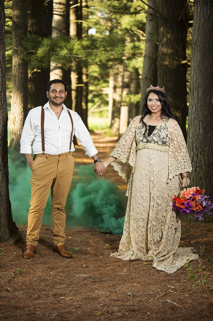 Boho wedding couple holds hands in front of green smoke bomb