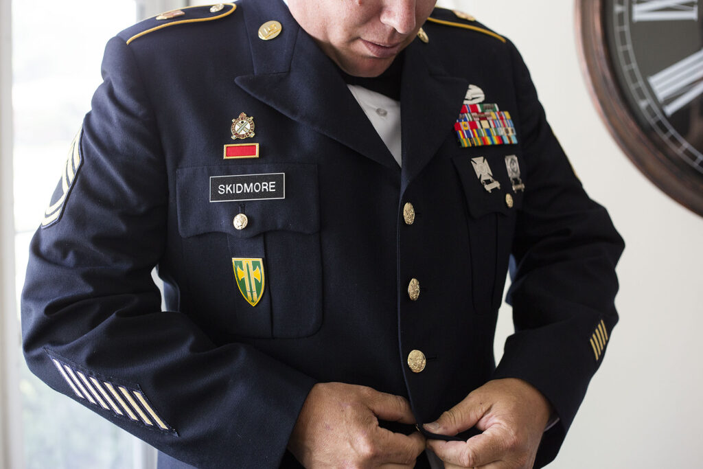 Groom buttons up his Army uniform before Belleville elopement