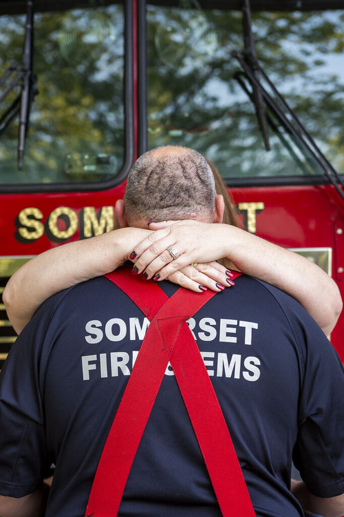 Bride to be wraps arms around future husband during fire department engagement session