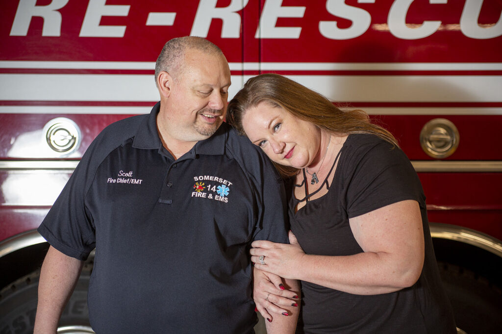 Couple snuggles up in front of fire engine during fire department engagement session