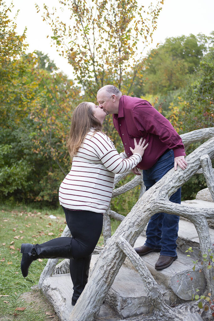 Jackson MI engaged couple kissing on stone bridge at McCourtie Park