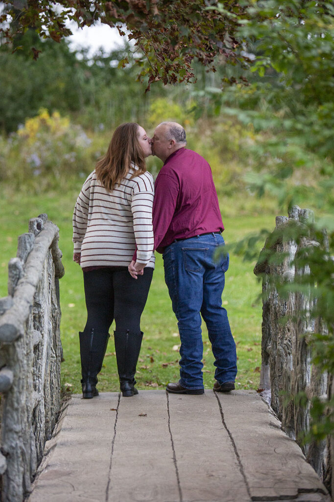 Fire department engagement couple kisses on bridge at McCourtie Park