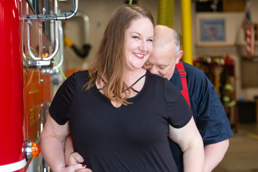 Groom to be kisses future bride's neck during fire department engagement session