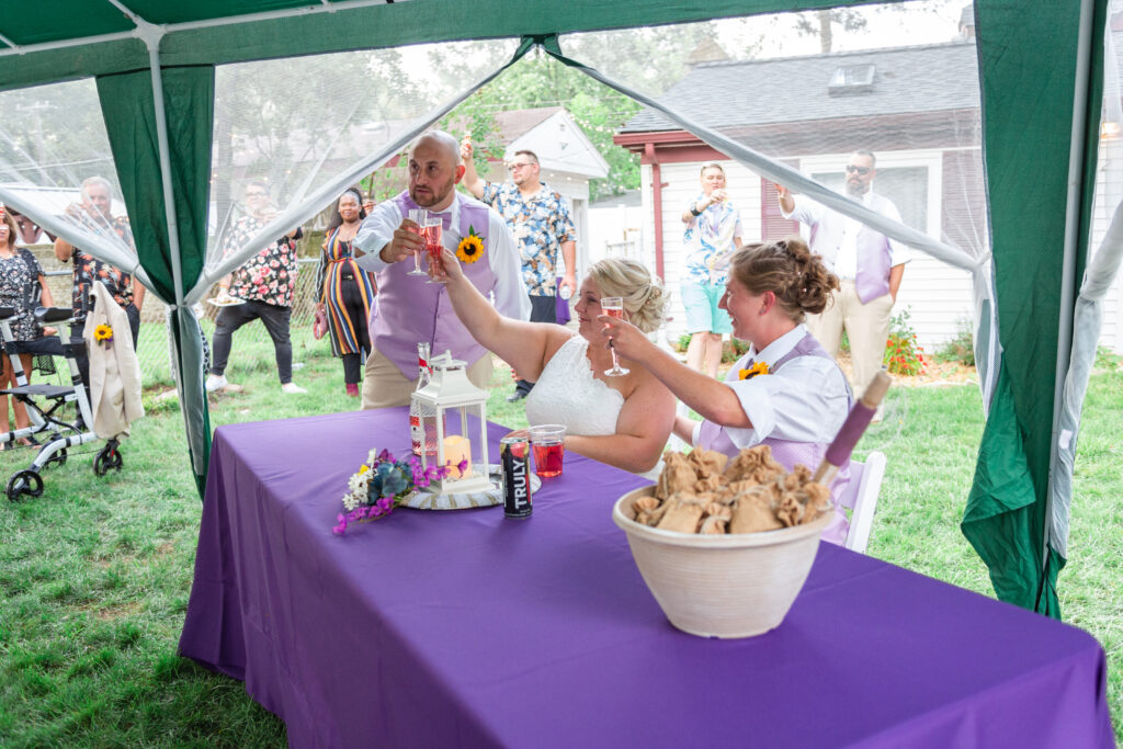 Michigan lesbian wedding couple toasts champagne with their best man during Westland wedding