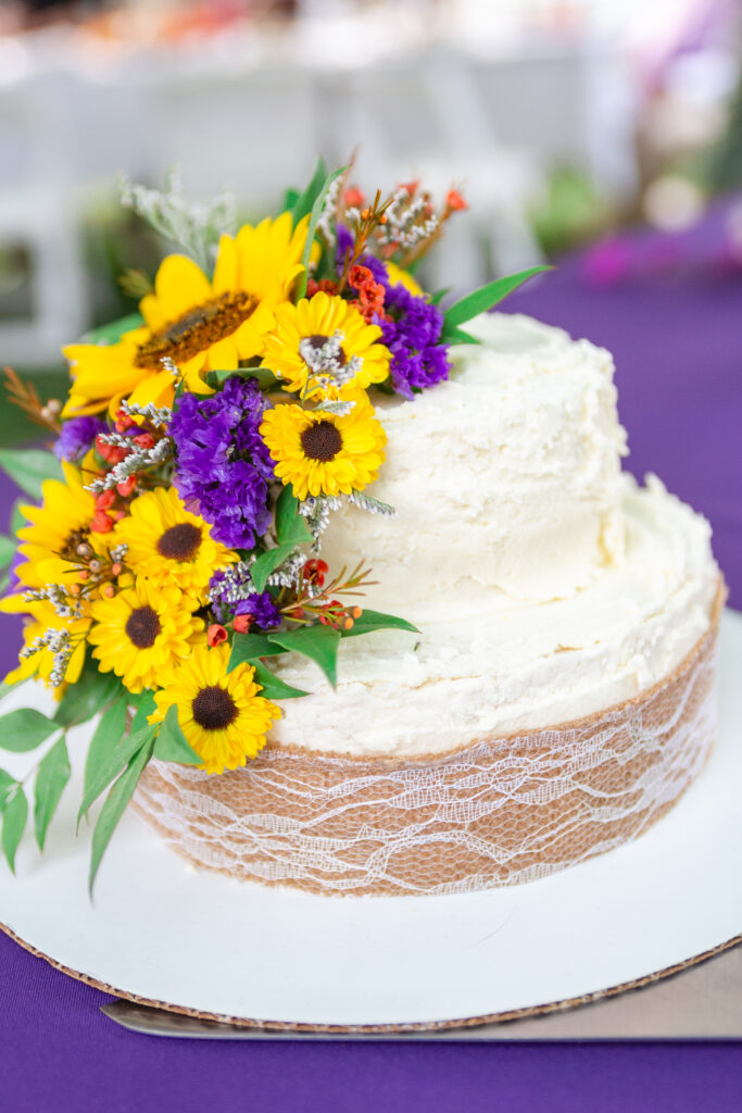 White wedding cake decorated with sunflowers and purple flowers Westland wedding