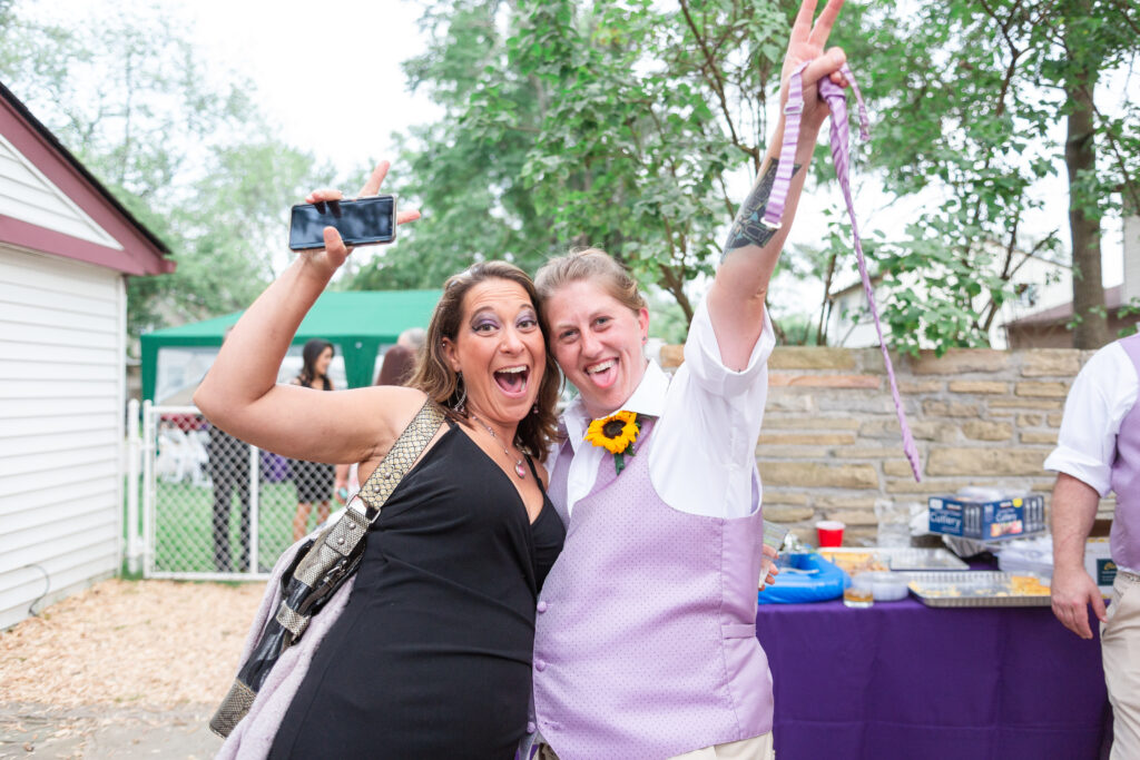 Bride and a guest throwing up peace signs while sticking their tongues out Westland wedding