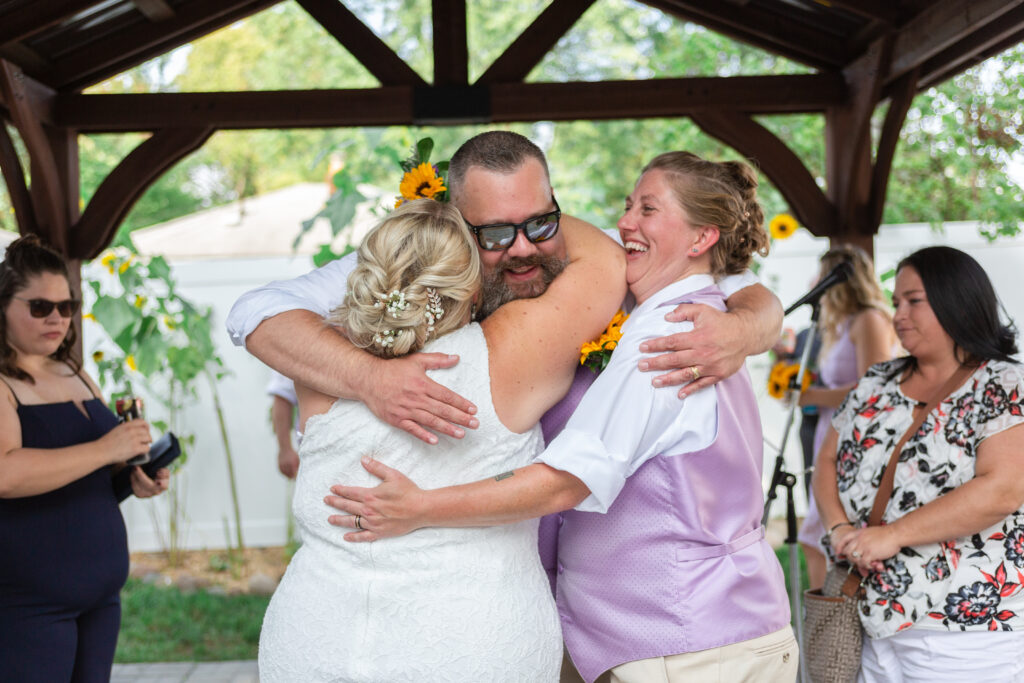 Same sex couple hugs guest after they're officially married Westland wedding