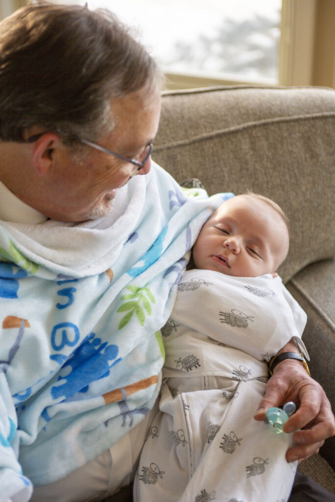 Grandpa holding grandson as he falls asleep before Michigan AirBNB wedding