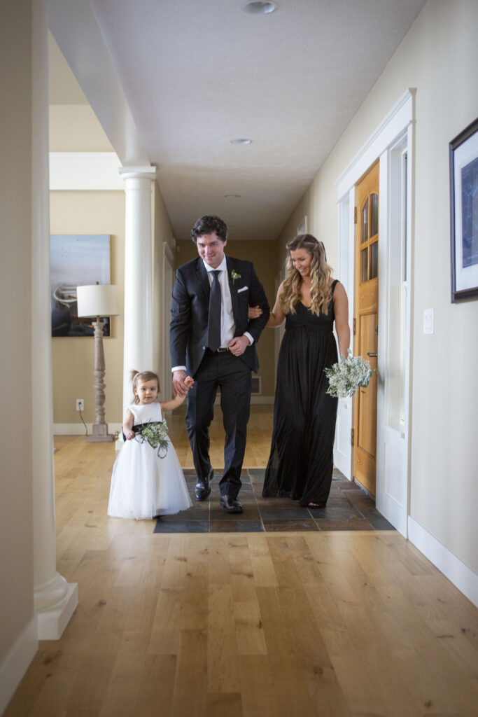 Flower girl accompanied by her parents, walk down the aisle during the Michigan AirBNB wedding